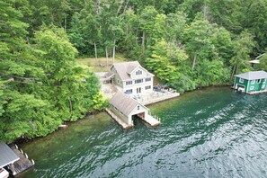 Une maison avec un quai s’avançant dans un lac, entourée d’une forêt dense.