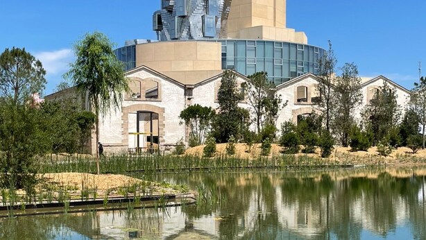 Un bâtiment moderne doté d’une conception architecturale unique, caractérisé par un mélange de formes géométriques et une façade en verre réfléchissant.