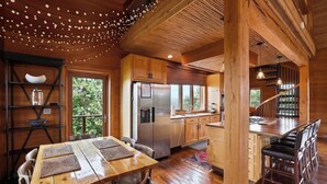 Un intérieur en bois comprenant une table à manger, des chaises, un coin cuisine et un escalier.