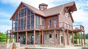 Une grande maison à étages, dotée d’une façade en verre remarquable, de fondations en pierre et d’une piscine située à l’avant.