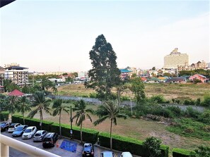 Hotel surrounded by lush greenery and palm trees, near a parking area.