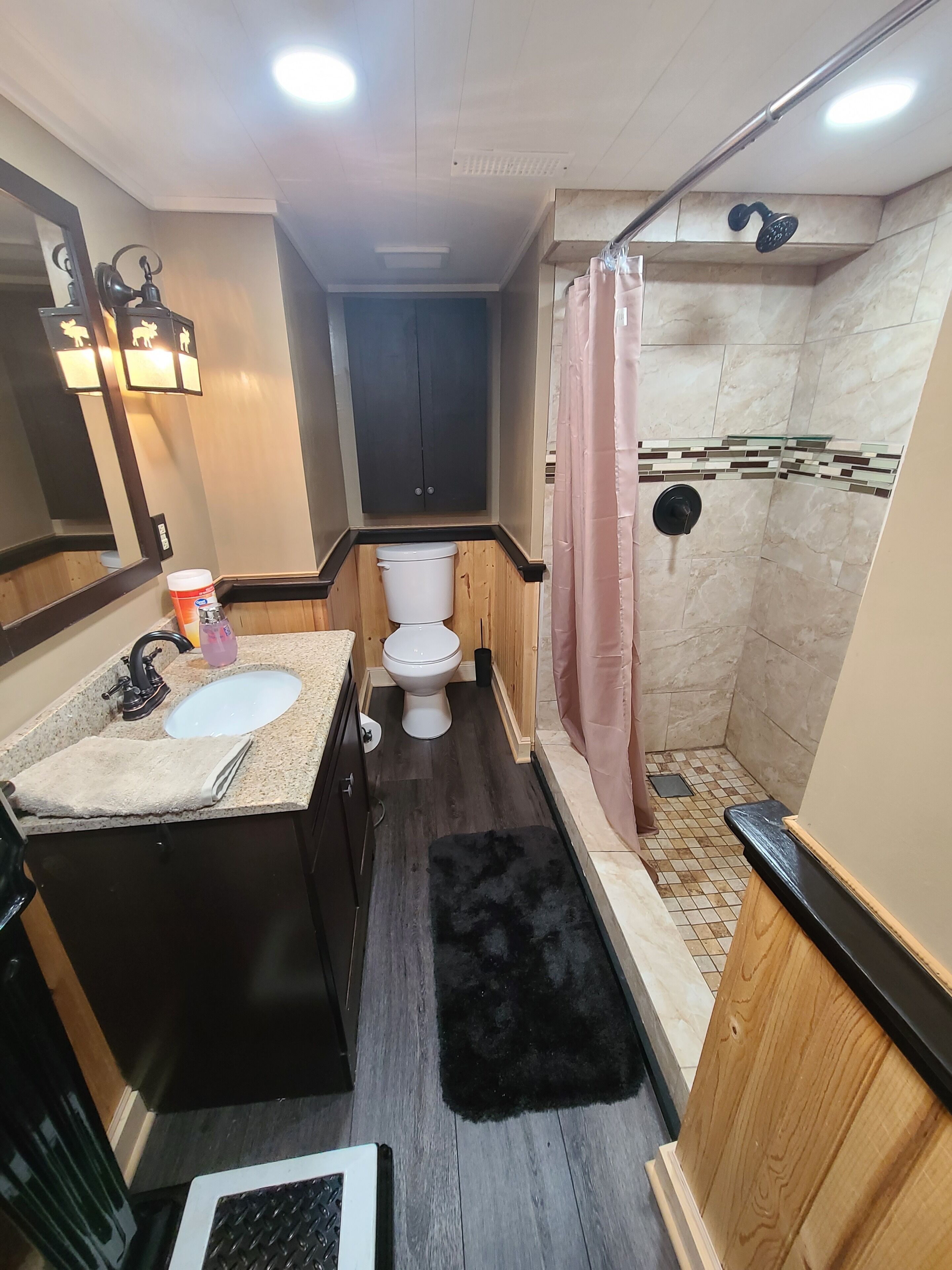 A compact bathroom with a sink, toilet, and shower.