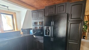 A kitchen with dark wood cabinets, a black refrigerator, and a built-in oven. - Lake home pontoon included.  (Clear Lake)