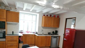 A kitchen with wooden cabinets, a red refrigerator, a sink, and a dining table with a tablecloth.
