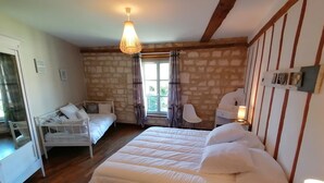 A bedroom with a large bed, a smaller bed, a desk, a chair, and a window with curtains.