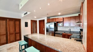 Uma cozinha moderna com bancadas de granito, eletrodomésticos de aço inoxidável e armários de madeira.