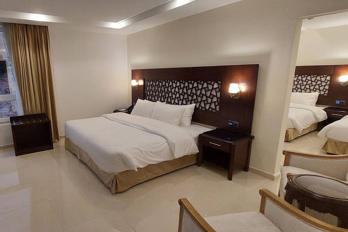 A hotel room with a large bed, bedside tables, a desk, and a chair.