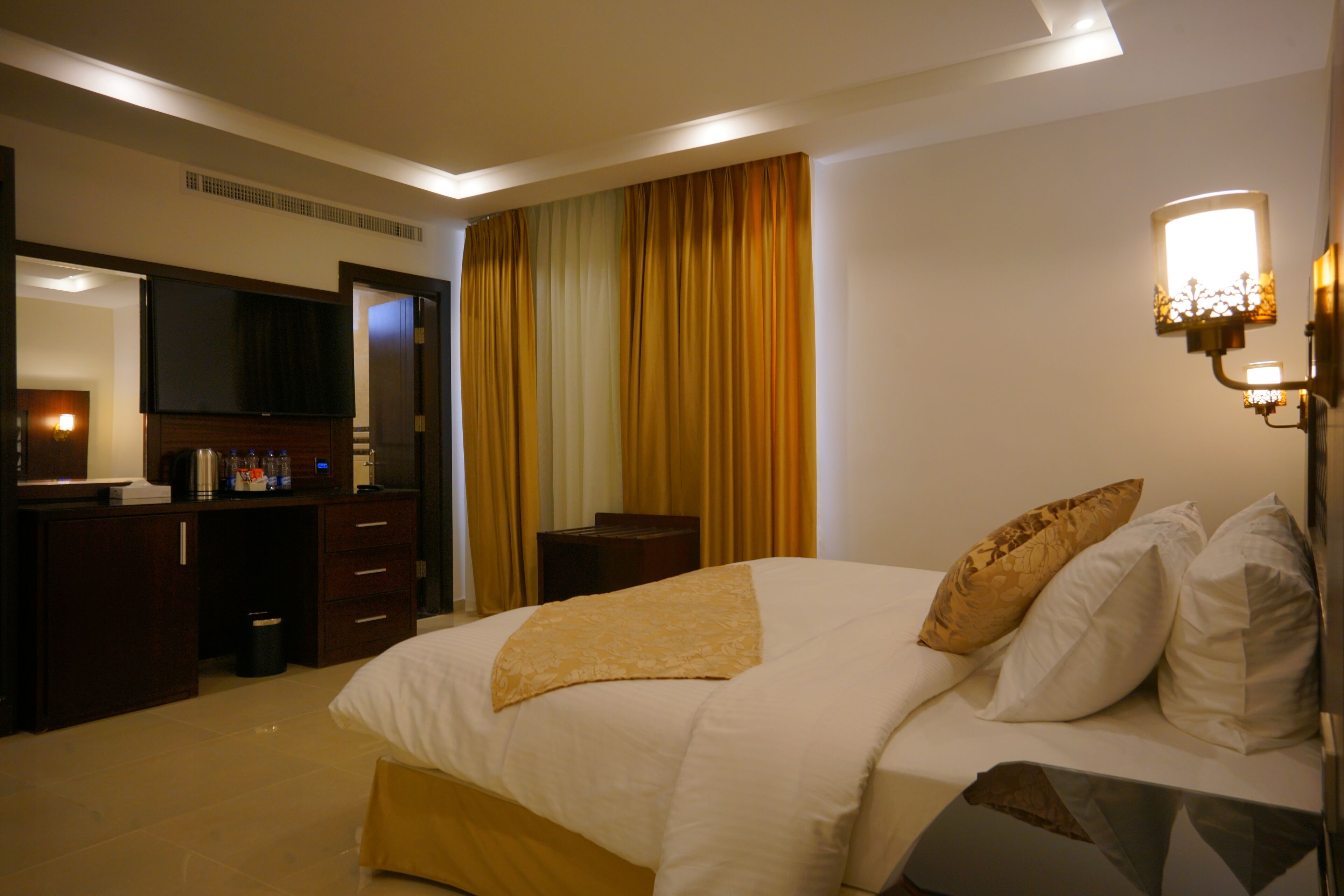 Une chambre d’hôtel dotée d’un grand lit, d’un bureau avec un téléviseur à écran plat, d’une machine à café et d’un mini-bar.