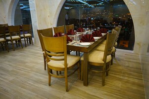 Un restaurante con sillas y mesas de madera, paredes de mármol y una decoración de diseño moderno.