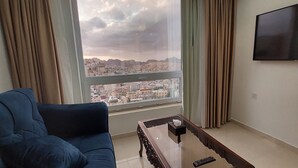 A living room with a sofa, a coffee table, and a TV mounted on the wall. - Petra Elite Hotel (Wadi Musa)