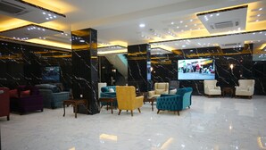 A lobby with marble flooring, modern furniture, and a large screen displaying a mall scene. - Petra Elite Hotel (Wadi Musa)