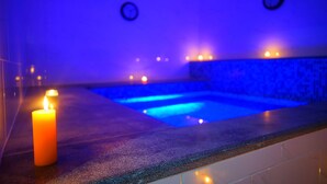 A spa area with a blue-lit pool, a lit candle, and two wall clocks. - Petra Elite Hotel (Wadi Musa)