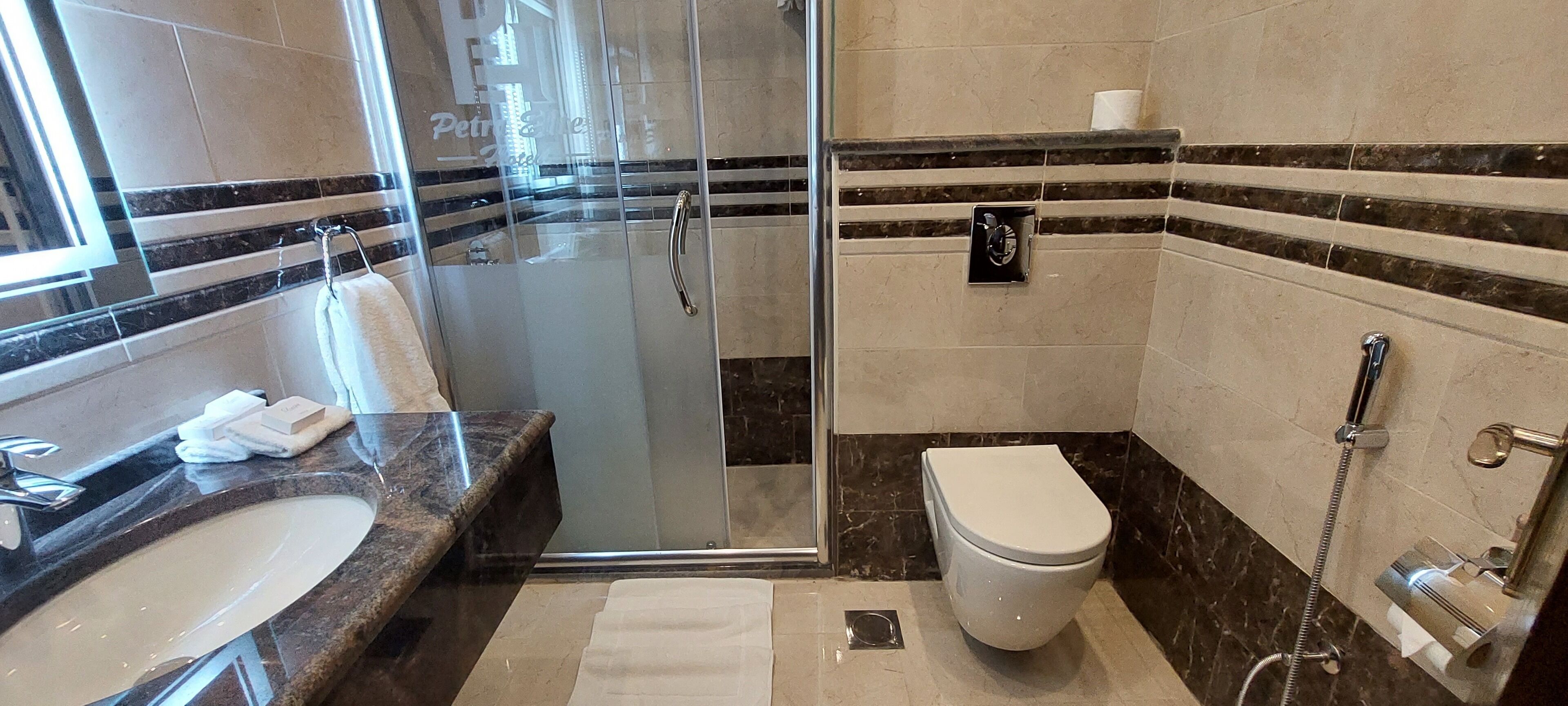 Une salle de bain dotée d’une douche à parois de verre, de toilettes et d’un lavabo avec un plan de travail en marbre.