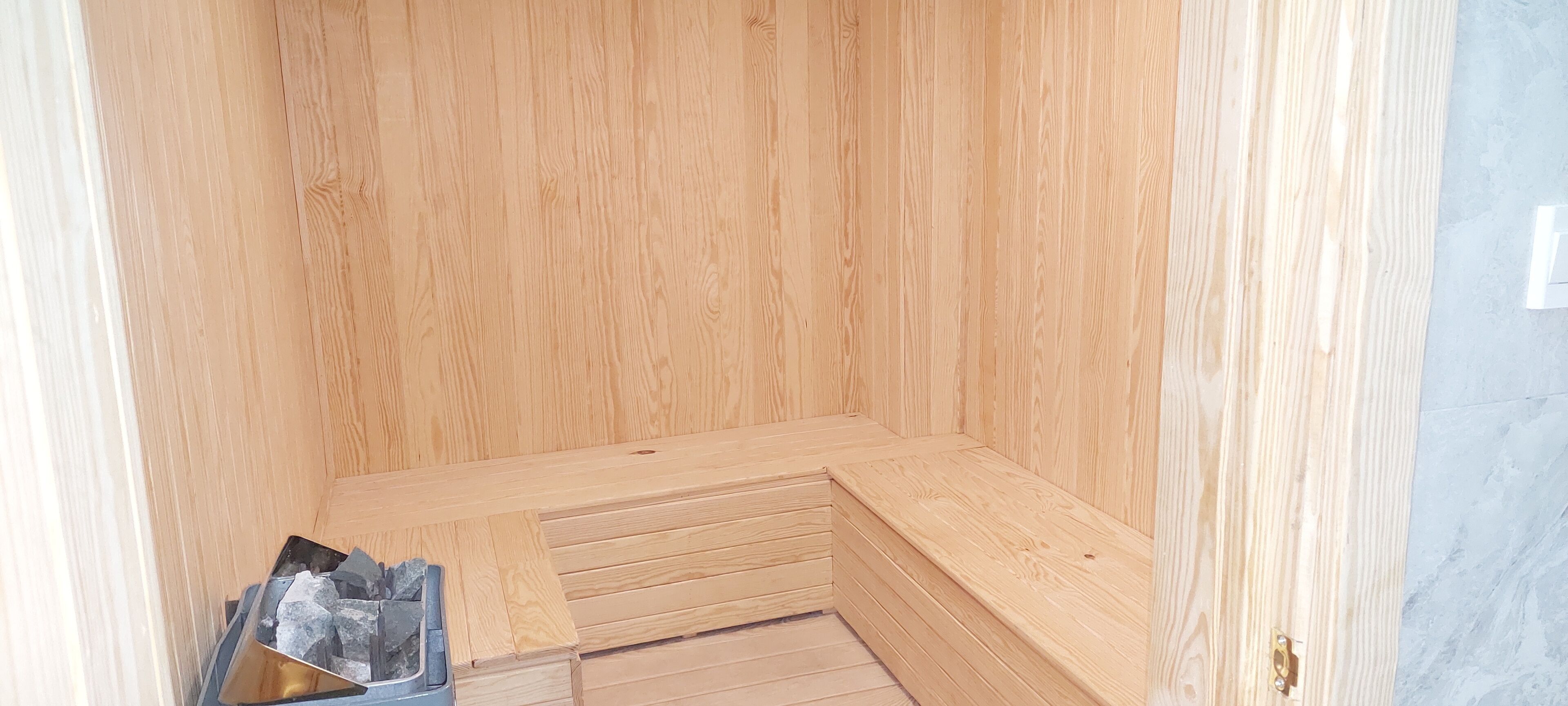 A wooden sauna with a bench and a small pile of stones.