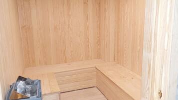 A wooden sauna with a bench and a small pile of stones.