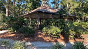 A gazebo with a tiled roof, surrounded by dense greenery and trees.