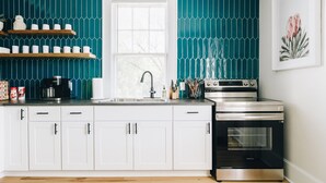 A kitchen with white cabinets, a black oven, and teal backsplash tiles.