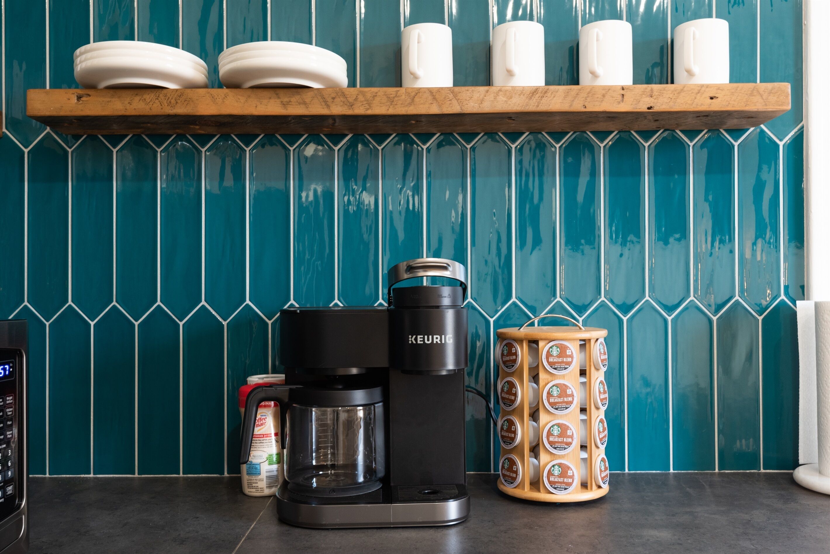 Una cafetera, un molinillo de café y una taza sobre una encimera de cocina.