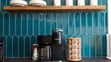 Una cafetera, un molinillo de café y una taza sobre una encimera de cocina.