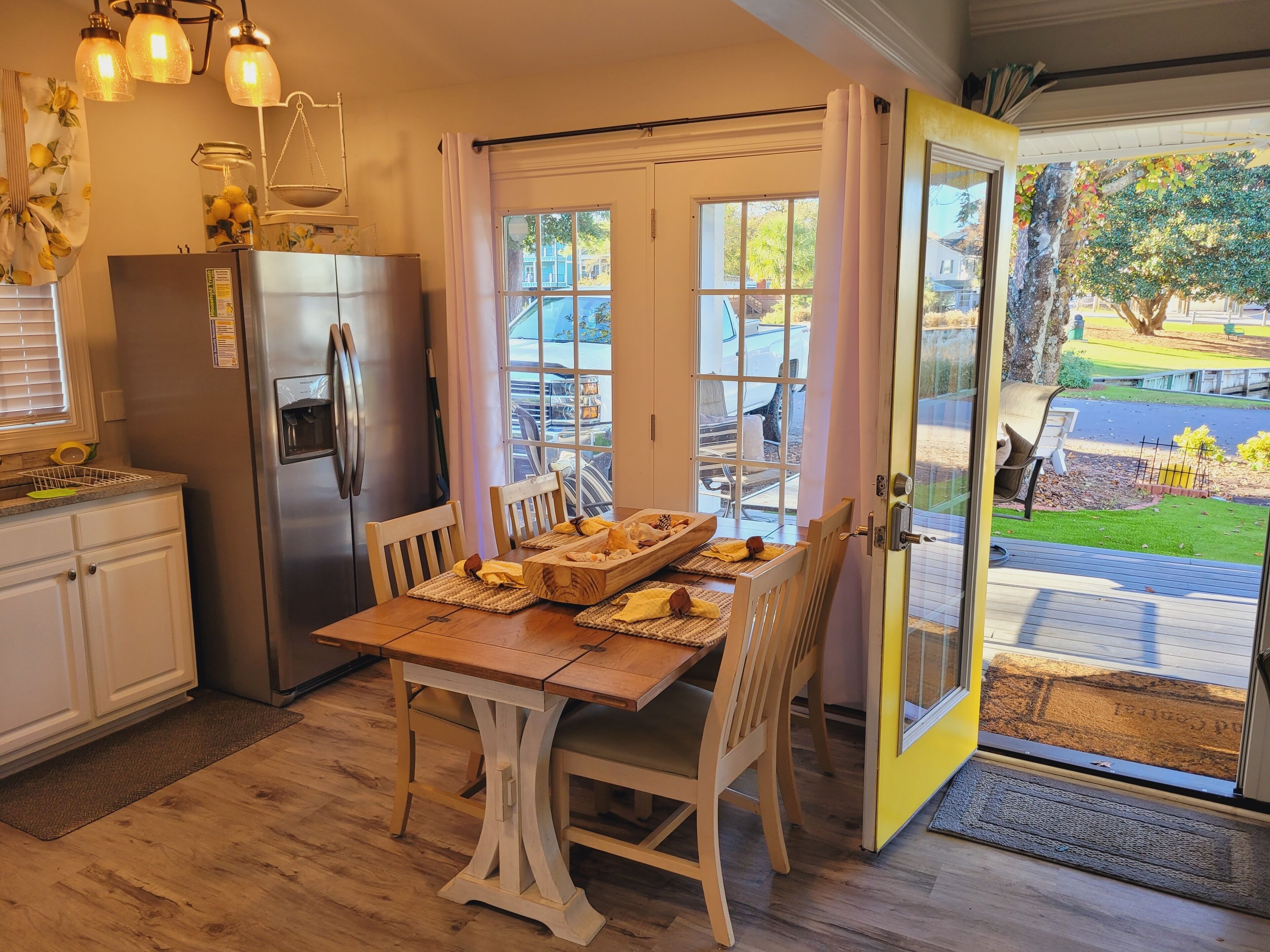 A kitchen with a wooden table, chairs, a refrigerator, and a window with a view of the outside.