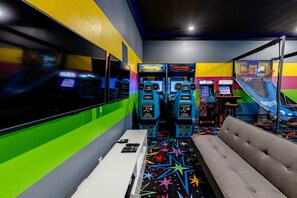 An arcade with multiple gaming machines, a bench, and a colorful play area.