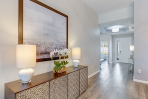 A hallway with a wooden console table, two lamps, and a large abstract painting.