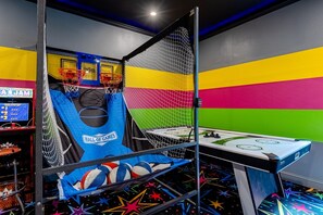 A colorful indoor play area with a basketball hoop, a climbing wall, and a table tennis table.