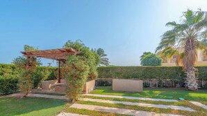 A garden with a pergola, a palm tree, and a hedge. - VESTA - Luxury Villa - 5BR - Sabina (Hurghada)