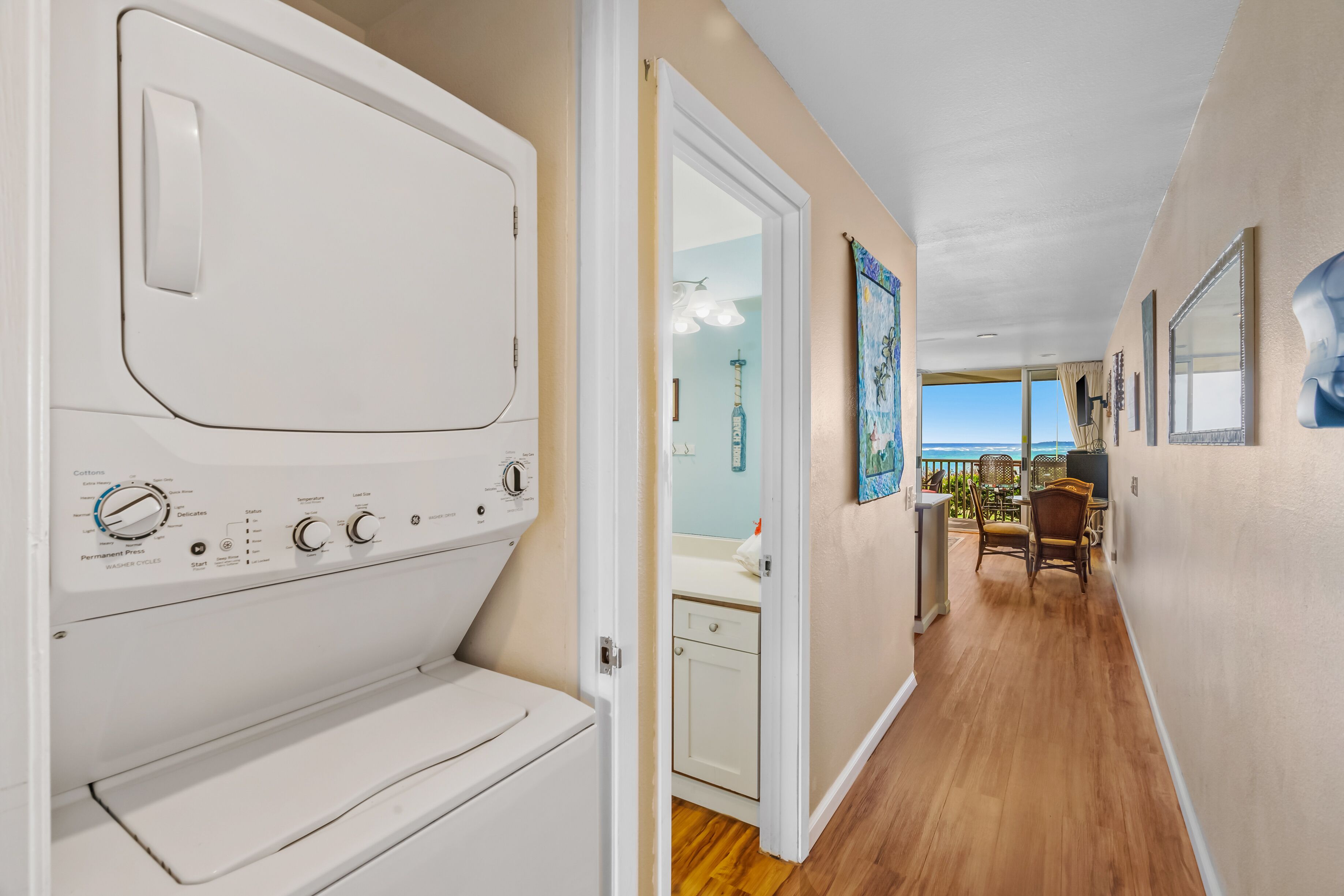 A laundry room with a washing machine and dryer, a bathroom with a toilet and sink, and a balcony with a view.