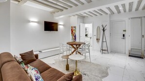 Ein modernes Wohnzimmer mit einem braunen Sofa, einem runden Holztisch und einem weißen Boden.