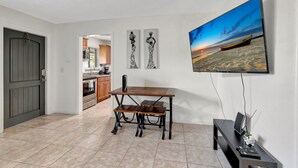 Una sala de estar moderna con comedor, televisor de pantalla plana y obras de arte en la pared.