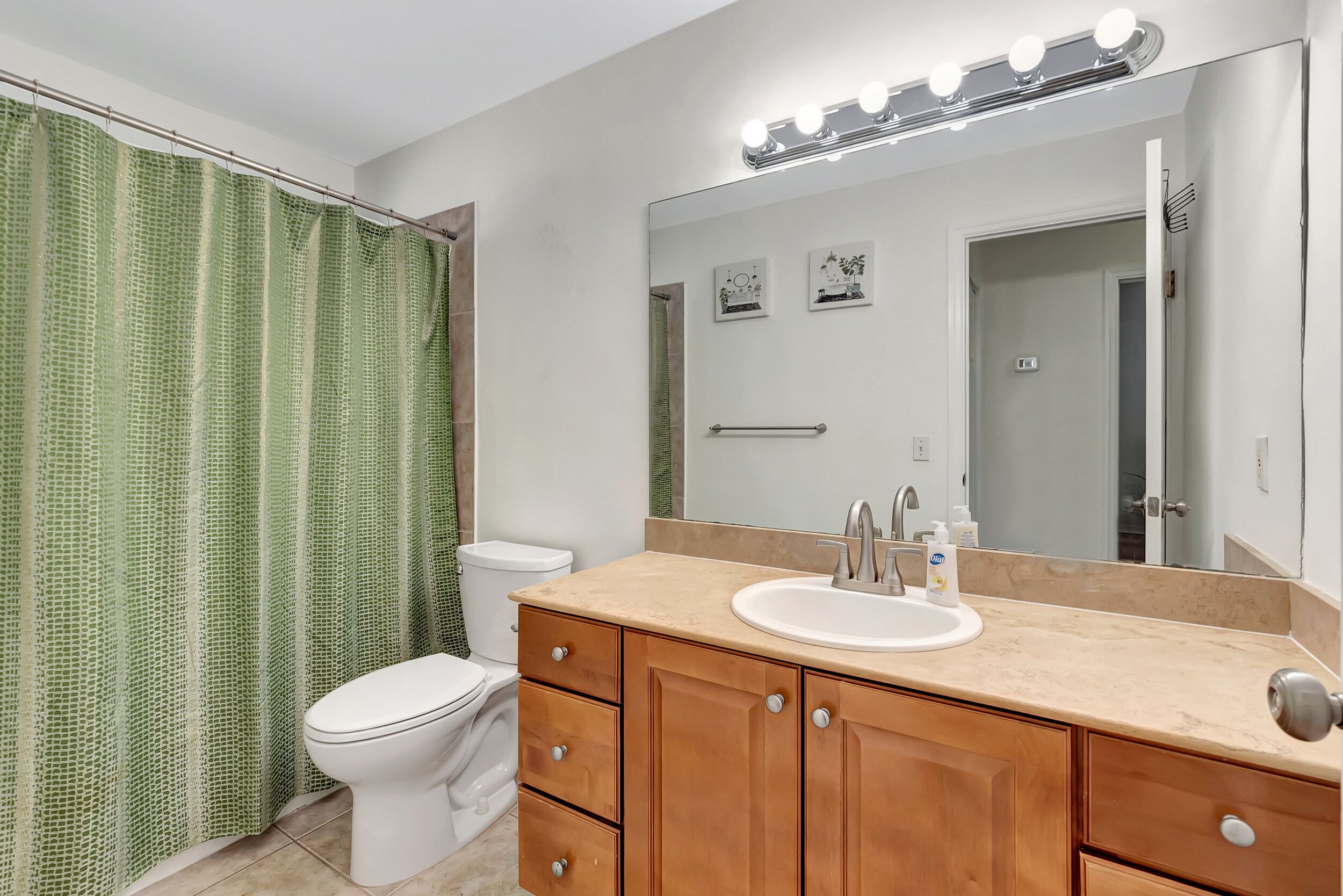 Une salle de bain avec des toilettes blanches, un lavabo beige et des meubles en bois.