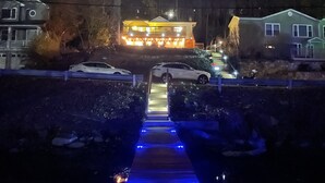 A residential driveway with two cars parked on either side, leading to a house with a lit porch and a staircase. - Lakeside Home w/Lake Access, Dock & Water Views! (Hopatcong)