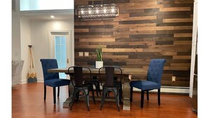 A dining area with a wooden wall, a chandelier, and a table with chairs. - Lakeside Home w/Lake Access, Dock & Water Views! (Hopatcong)