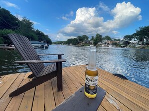 Une jetée en bois avec une chaise et une bouteille de bière Corona Premier.