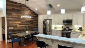 A modern kitchen with a wooden accent wall, stainless steel appliances, and a bar area. - Lakeside Home w/Lake Access, Dock & Water Views! (Hopatcong)