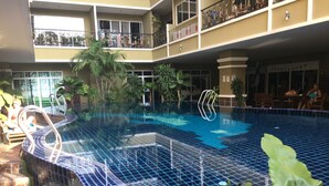 An indoor swimming pool with a tiled floor, surrounded by plants and a seating area. - Pratumnak 1 bed With sea View at Siam Oriental Twins (Pattaya)