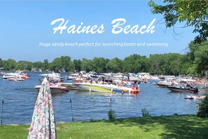 A beach with numerous boats and people, indicating a popular boating and swimming location.