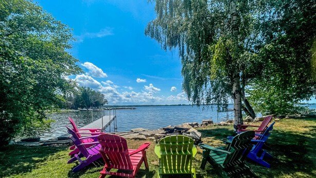 Une vue sur le lac, avec des chaises Adirondack aux couleurs vives et un quai.