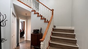 Un escalier avec des marches en bois et des balustrades blanches, menant à l’étage supérieur.