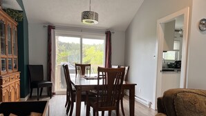 Un coin repas avec une table et des chaises en bois, un buffet et une vue dégagée sur l’extérieur grâce à une grande fenêtre.