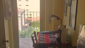 Una cocina con estufa, una mesa con mantel, una silla y vistas a un edificio.