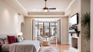 A spacious bedroom with a large bed, a curved seating area, and a fireplace.
