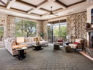 A spacious living room with a sofa, armchairs, a coffee table, and a fireplace.
