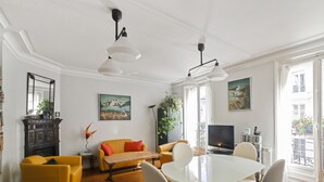 A modern living room with a dining table, yellow sofas, and a TV.