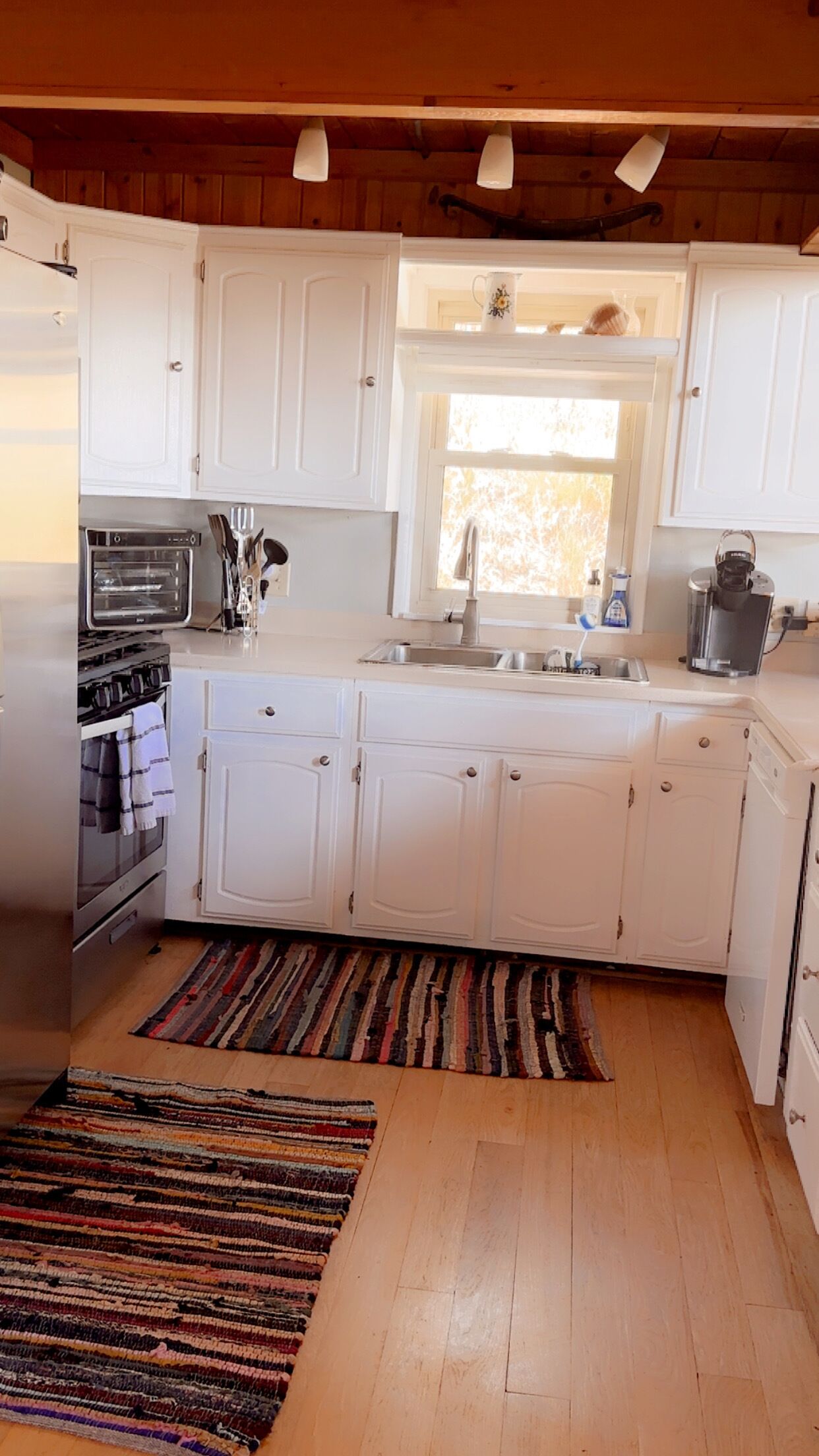 A kitchen with white cabinets, a built-in oven, a sink, and a window above the counter.