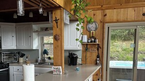 Una cocina con armarios de madera, una isla grande con taburetes, una planta colgante y vistas al exterior.