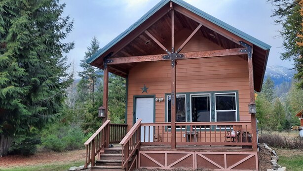 A wooden cabin with a porch, a staircase, and a door.
