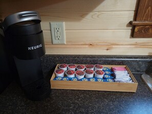 Keittiön työtasolla on Keurig-kahvinkeitin, kahvikapselihylly ja puinen laatikko, jossa on kahvikapseleita.