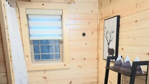 Pieni, puinen mökkityylinen kylpyhuone, jossa on wc, pesuallas ja ikkuna.